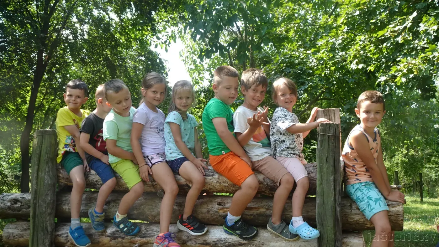 Deti sedia na drevenej lavici pri plote
